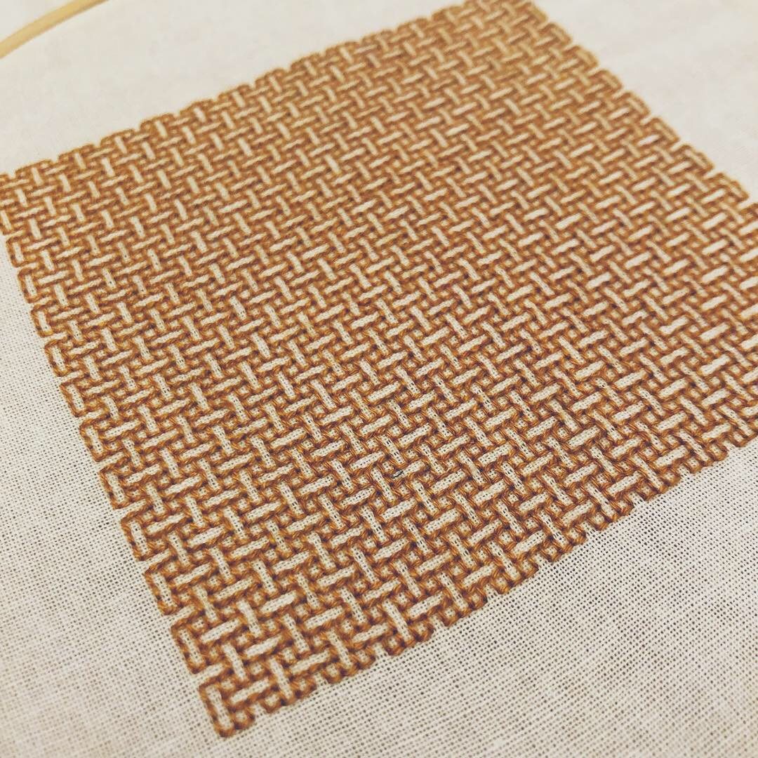 A close-up of the square of amber embroidery in a weave pattern, on white fabric